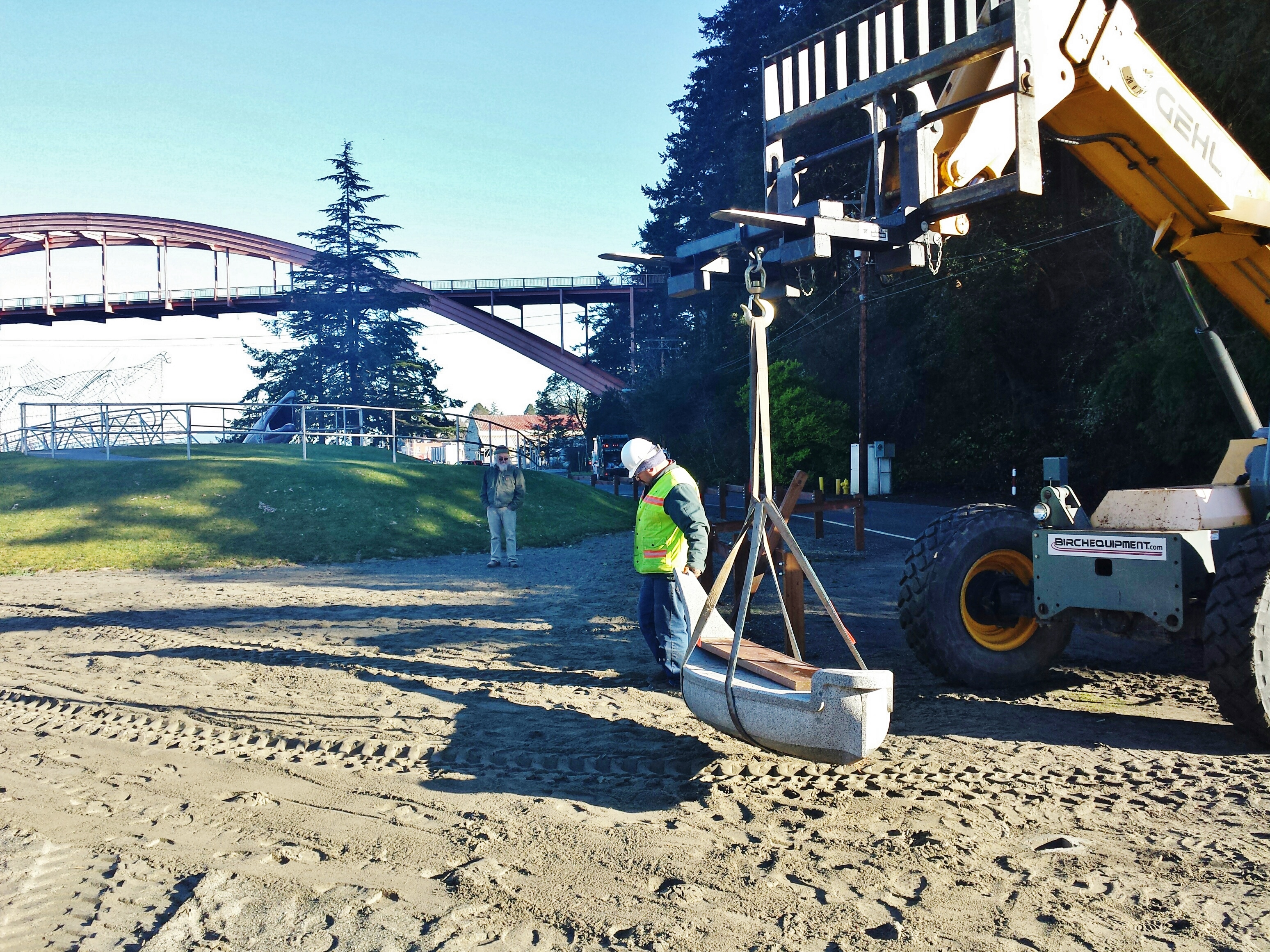 A La Conner City employee steadies the canoe as the forklift moves it to its new channel side pad. Tracy Powel watches from a safe distance.