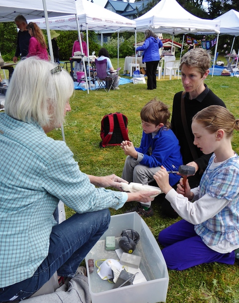 Sculptor Gudrun Ongman shows a young visitor how to carve stone. Photo by Eva Kozun.
